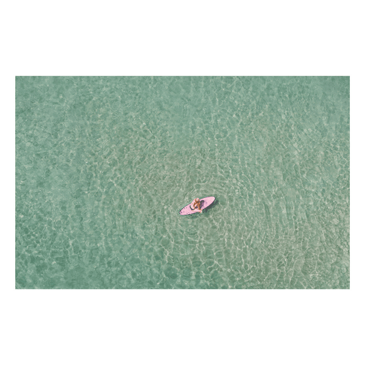 Aerial view of a lone surfer on a pink surfboard floating in the crystal-clear waters of Toowoon Bay Beach. The serene ocean scene captures the essence of calm and patience, making it a perfect addition to any coastal-inspired space.
