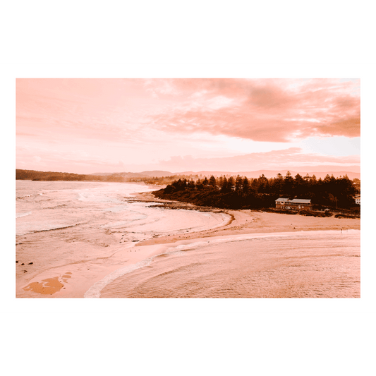 Aerial view of Toowoon Bay Beach bathed in soft pink hues, capturing a serene coastal landscape at sunset. The warm tones highlight the shoreline, waves, and surrounding scenery, making it a perfect addition to any beach-inspired space.
