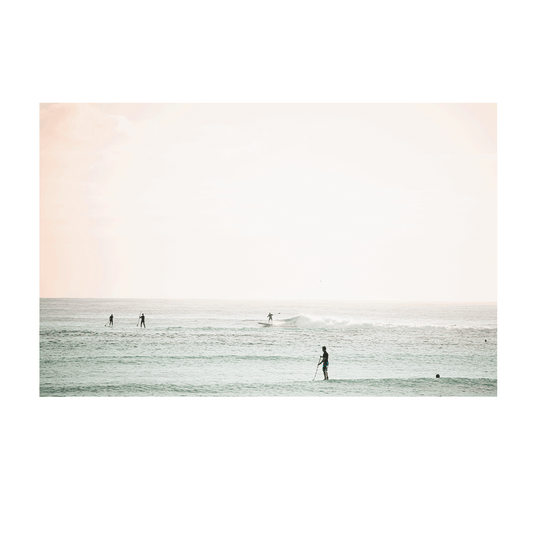 A serene coastal scene of Toowoon Bay Beach, featuring paddleboarders and surfers gliding across pastel-hued waters. A soft, minimalist ocean print perfect for adding a calming beachside aesthetic to any space.
