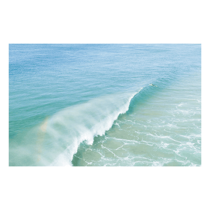 📸 An aerial view of a breaking wave at Wamberal Beach, NSW, with a soft rainbow appearing in the mist and pastel blue-green ocean hues.
