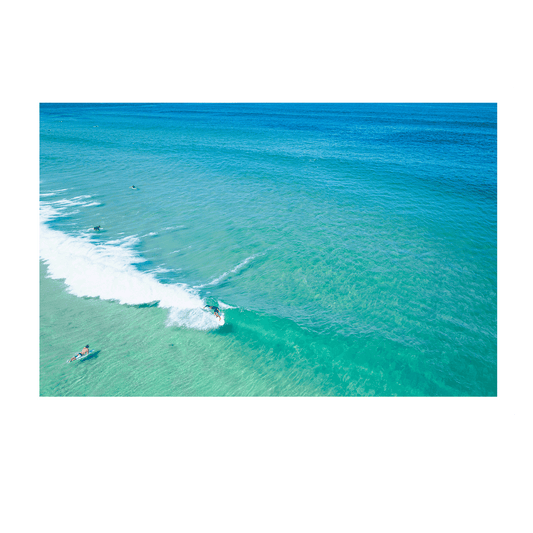 📸 An aerial view of Wamberal Beach, NSW, featuring a surfer riding a perfect wave while others float in tranquil turquoise waters.
